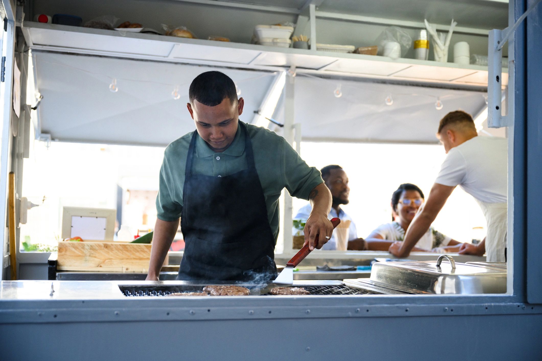 Flipping burgers on grill in urban food truck