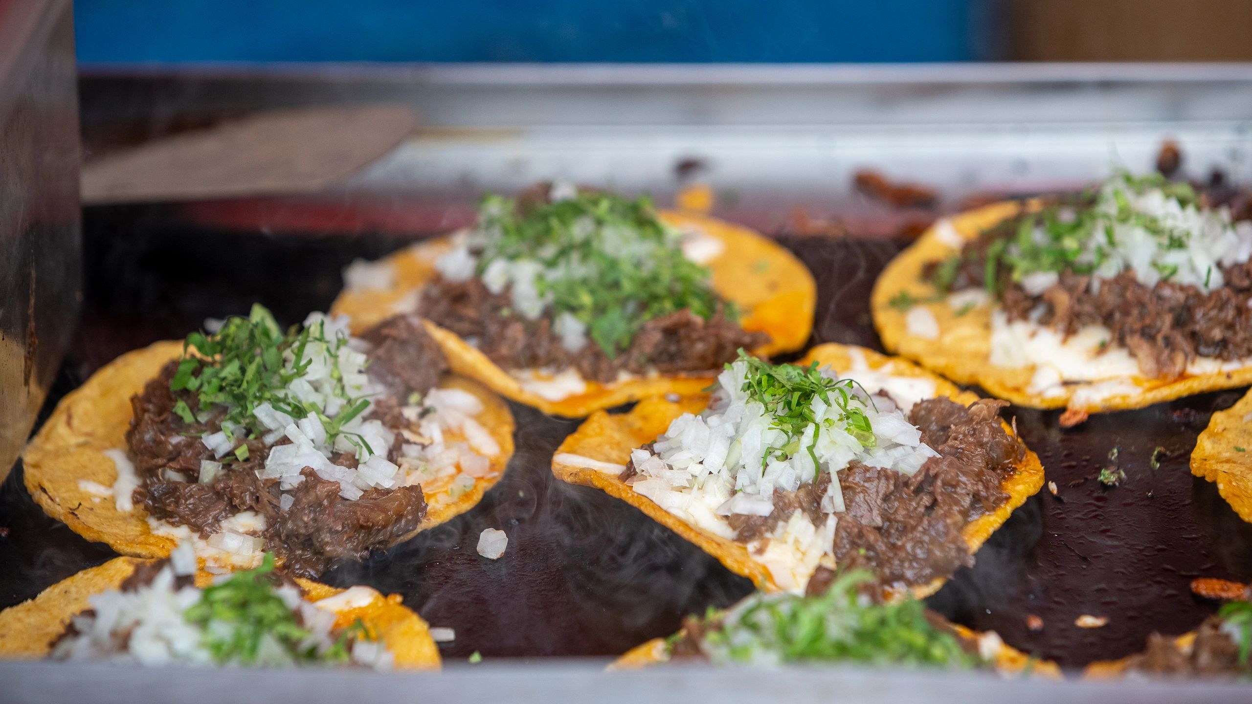 Traditional Mexican tacos with beef onions and cilantro on griddle